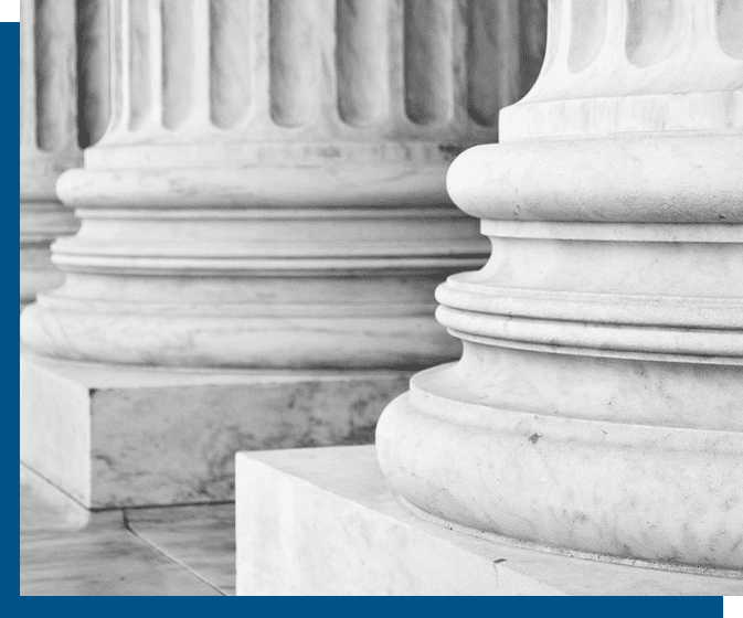 Close-up view of large, white marble columns and their bases in a classical architectural style.